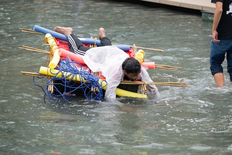 Student laying face down on colorful raft floating in shallow pool to take part in Ditch Day.