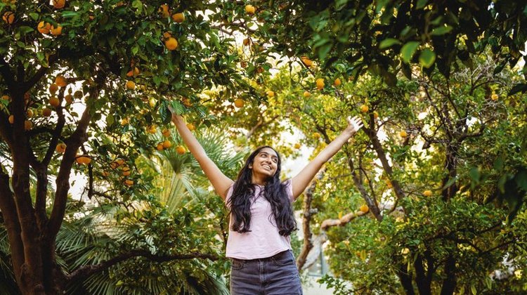 A Caltech student surrounded by trees and greenery.